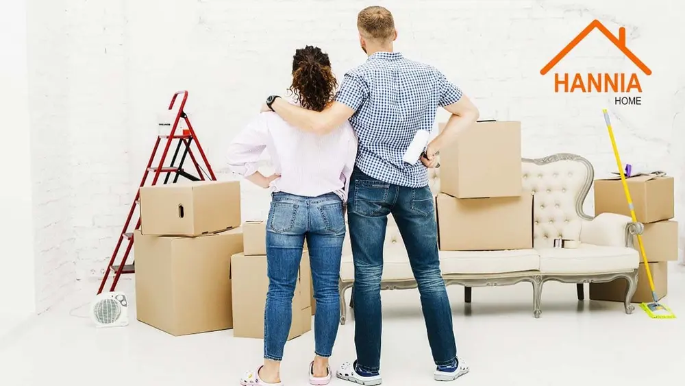 Pareja mirando un ambiente para remodelar, con cajas y una escalera